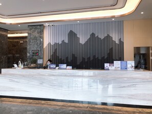 A hotel reception area with a marble counter, a large wall mural, and informational signs. - Ibis Styles Nanjing Dongqi Road Hotel (Nanjing)