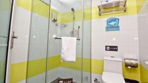 Un baño con cabina de ducha de vidrio, inodoro y secador de manos.
