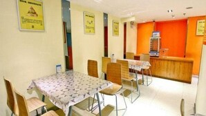 Un área de comedor con mesas y sillas, una recepción y carteles informativos en las paredes.