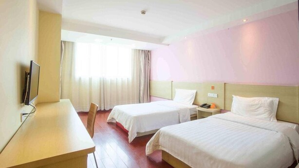A hotel room with two beds, a desk, a television, and a window with curtains. - 7 Days Inn Railway Station San Xiang Market Branch (Changsha)