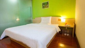 A hotel room with a bed, a nightstand, and a green wall. - 7 Days Inn Railway Station San Xiang Market Branch (Changsha)