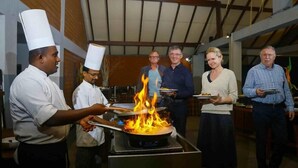 Um grupo de pessoas em uma cozinha com uma chama grande em uma panela.