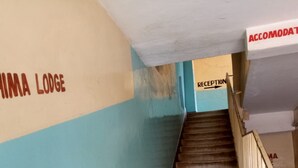 A staircase with a reception area at the top, walls painted in blue and beige, and a sign that reads "ACCOMMODATION". - Heshima Lodge (Naivasha)