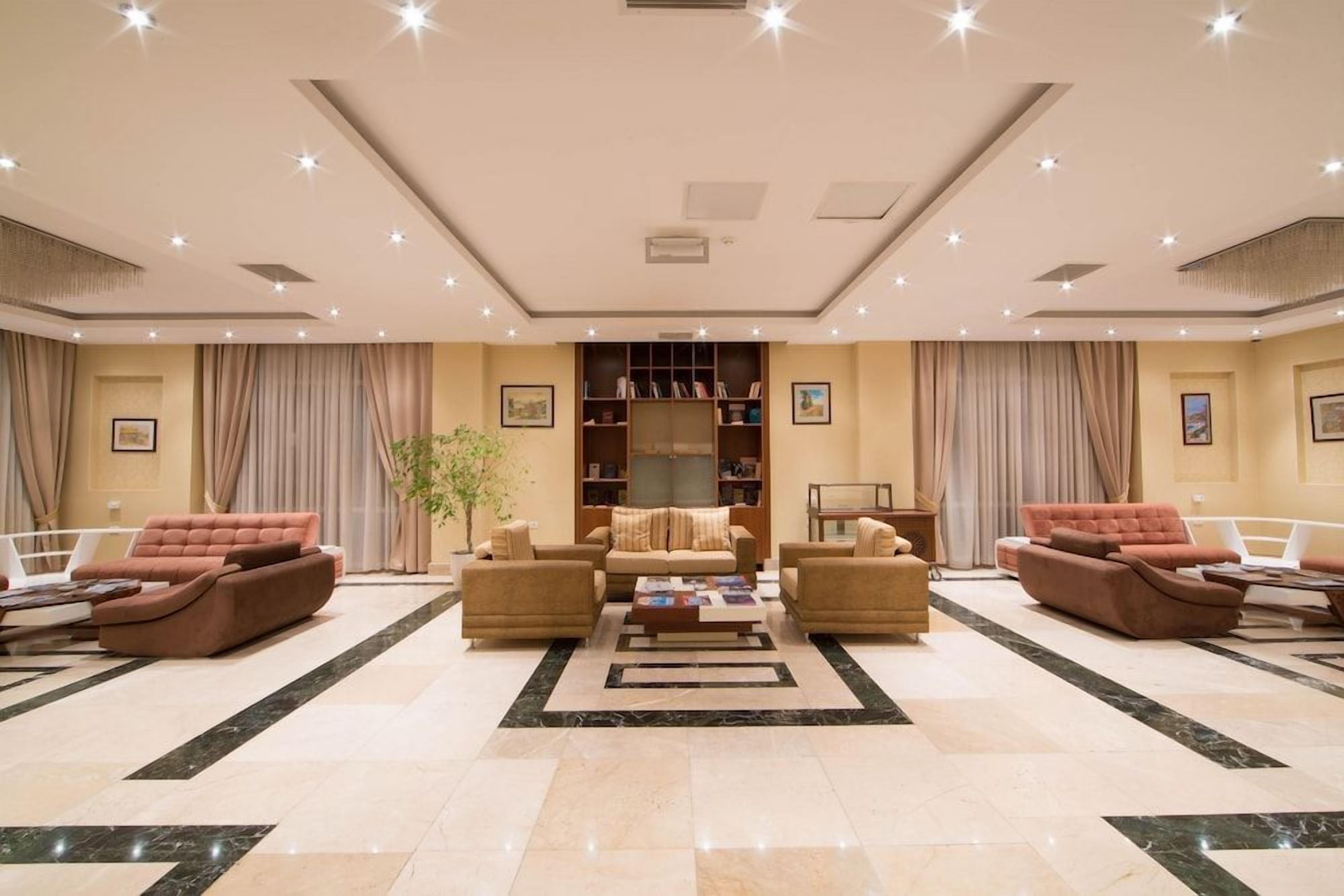 A spacious living area with a central coffee table, sofas, and a bookshelf.
