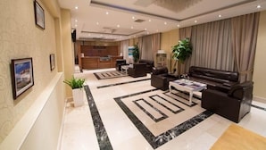 A spacious lobby with a reception desk, seating area, and a kitchen in the background. - Gabala City Hotel (Gabala)