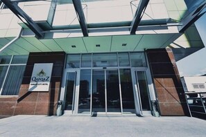 A hotel entrance with a glass facade, a signboard, and a clear sky. - Gabala City Hotel (Gabala)