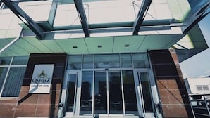The exterior of Qafqaz Gabala City Hotel with a modern glass entrance and a signboard. - Gabala City Hotel (Gabala)