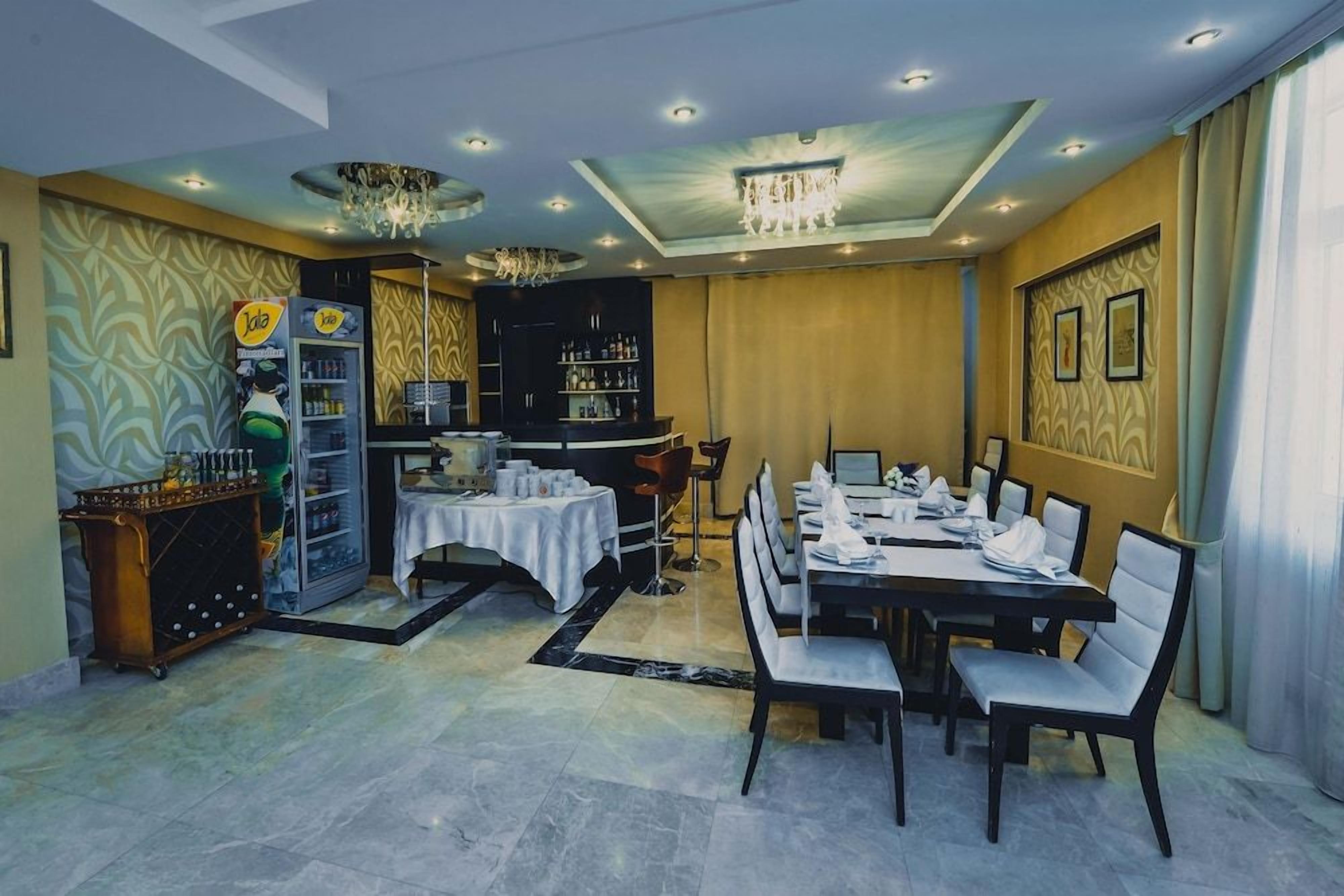 A restaurant with a bar area, a chandelier, and a dining setup with tables and chairs.