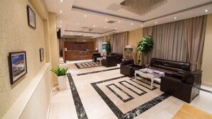 Un vestíbulo de hotel con mostrador de recepción, zona de estar y mostrador de información.