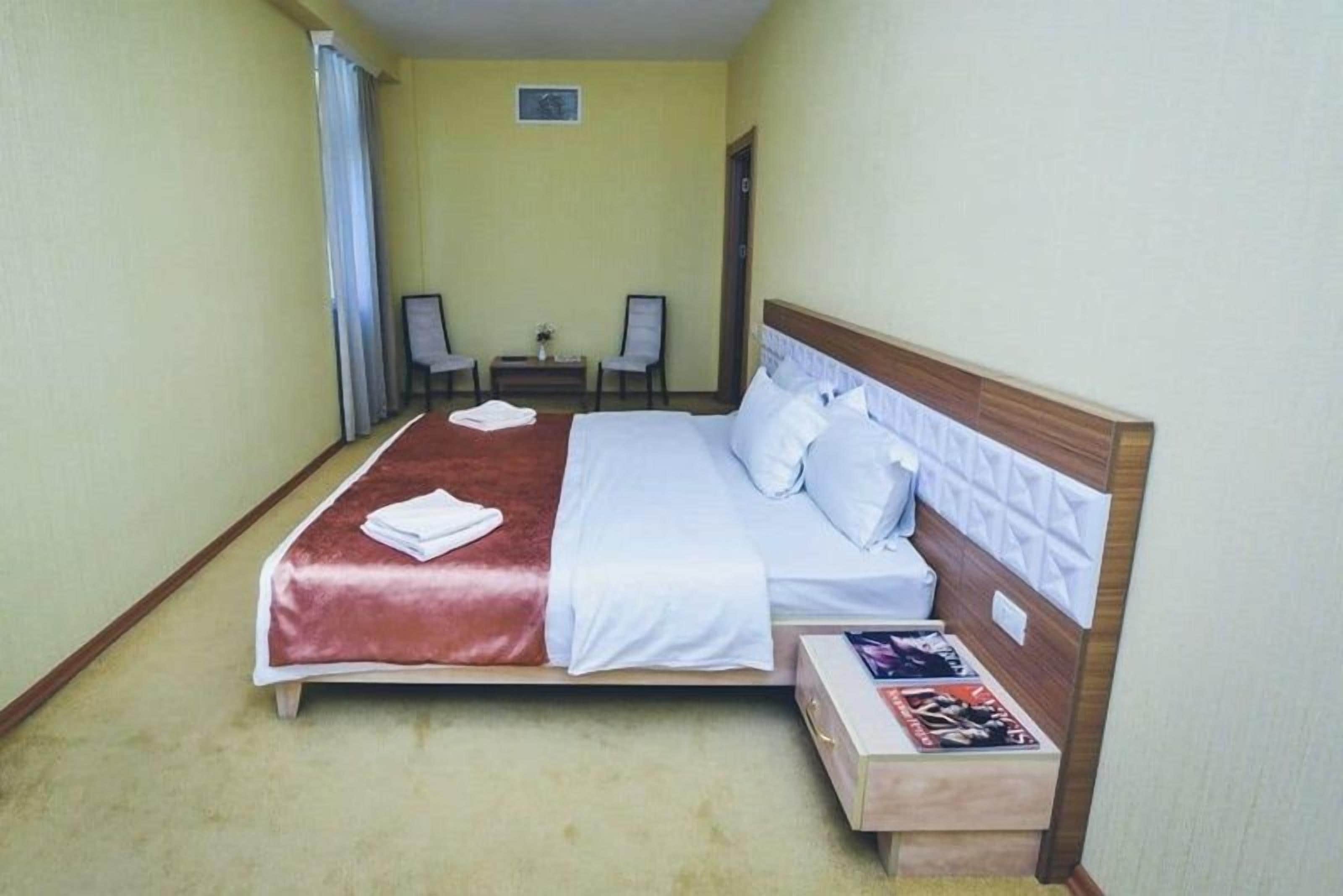 A hotel room with a bed, bedside tables, a chair, and a small table.