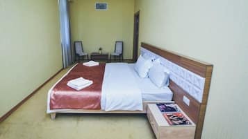 A hotel room with a bed, bedside tables, a chair, and a small table.