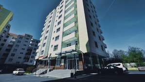 Un edificio de varios pisos con fachada de vidrio, una escalera que conduce a la entrada y un cielo despejado.