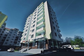 A multi-story building with a glass facade, a set of stairs leading to the entrance, and a clear sky. - Gabala City Hotel (Gabala)