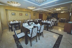 Comedor con mesas dispuestas para el servicio, destacando un papel tapiz decorativo y candelabros.