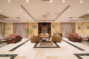 A spacious living room with a central coffee table, sofas, and a bookshelf. - Gabala City Hotel (Gabala)