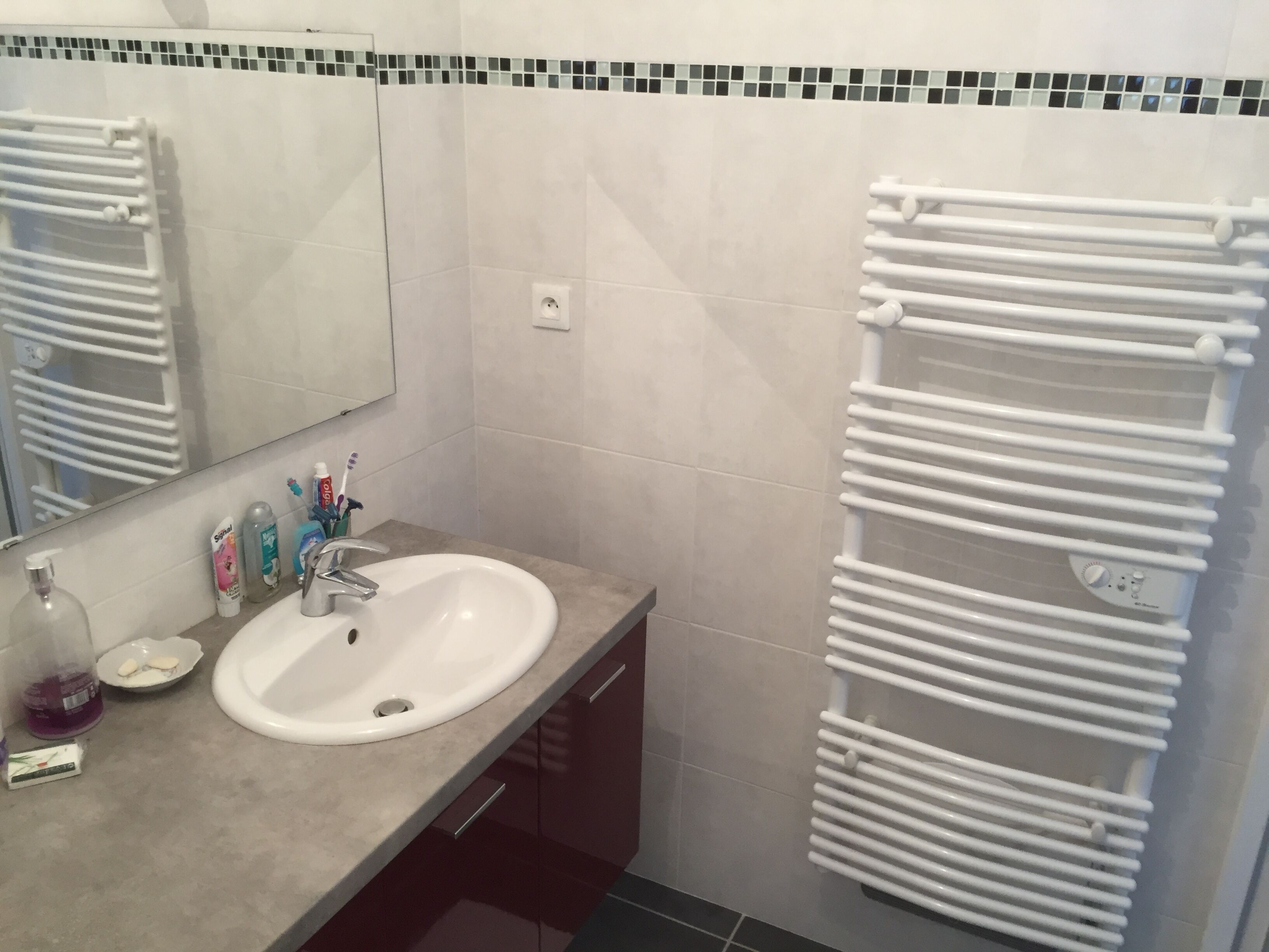 A bathroom with a white sink, a mirror, and a towel rack.