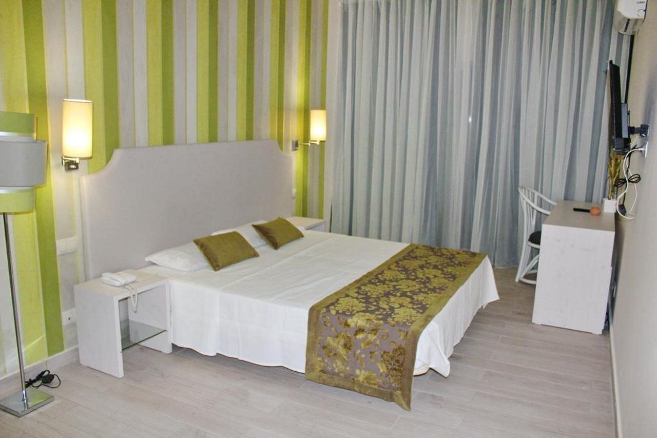 A hotel room with a bed, bedside table, lamp, and a desk with a chair.