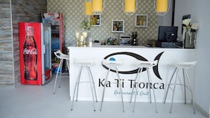 A restaurant bar area with a Coca-Cola vending machine, bar stools, and a counter with a logo. - Ouril Hotel Agueda (Boa Vista)