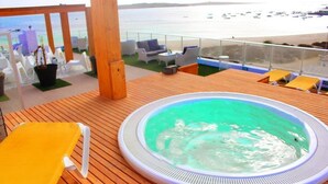 A hot tub on a wooden deck with a view of the sea and boats. - Ouril Hotel Agueda (Boa Vista)