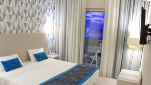 A hotel room with a bed, a nightstand, a lamp, and a view of the outdoors. - Ouril Hotel Agueda (Boa Vista)