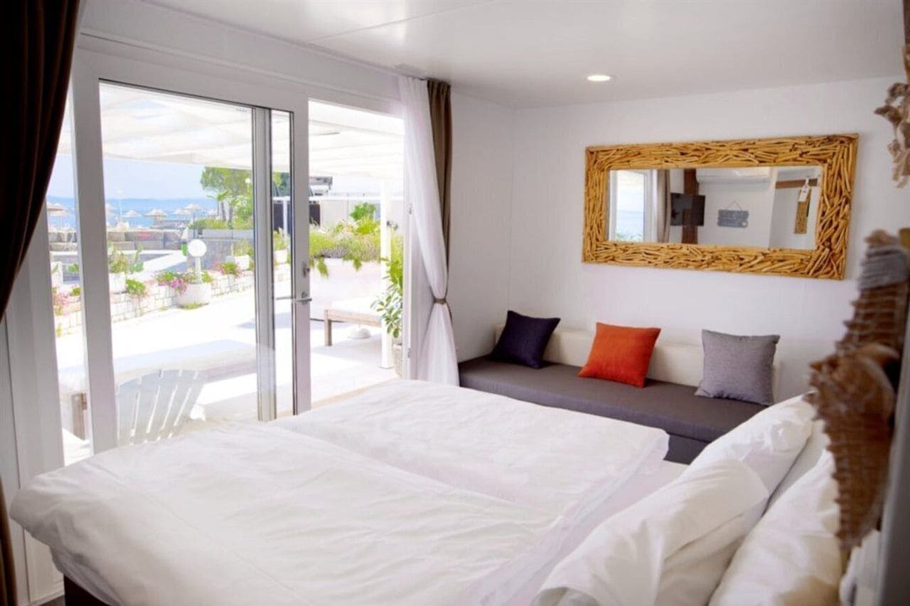 Camera d'albergo con un letto, un divano, uno specchio grande e vista sull'esterno.