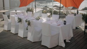 Una terraza con mesas dispuestas para una recepción de boda, con vista a un cuerpo de agua.