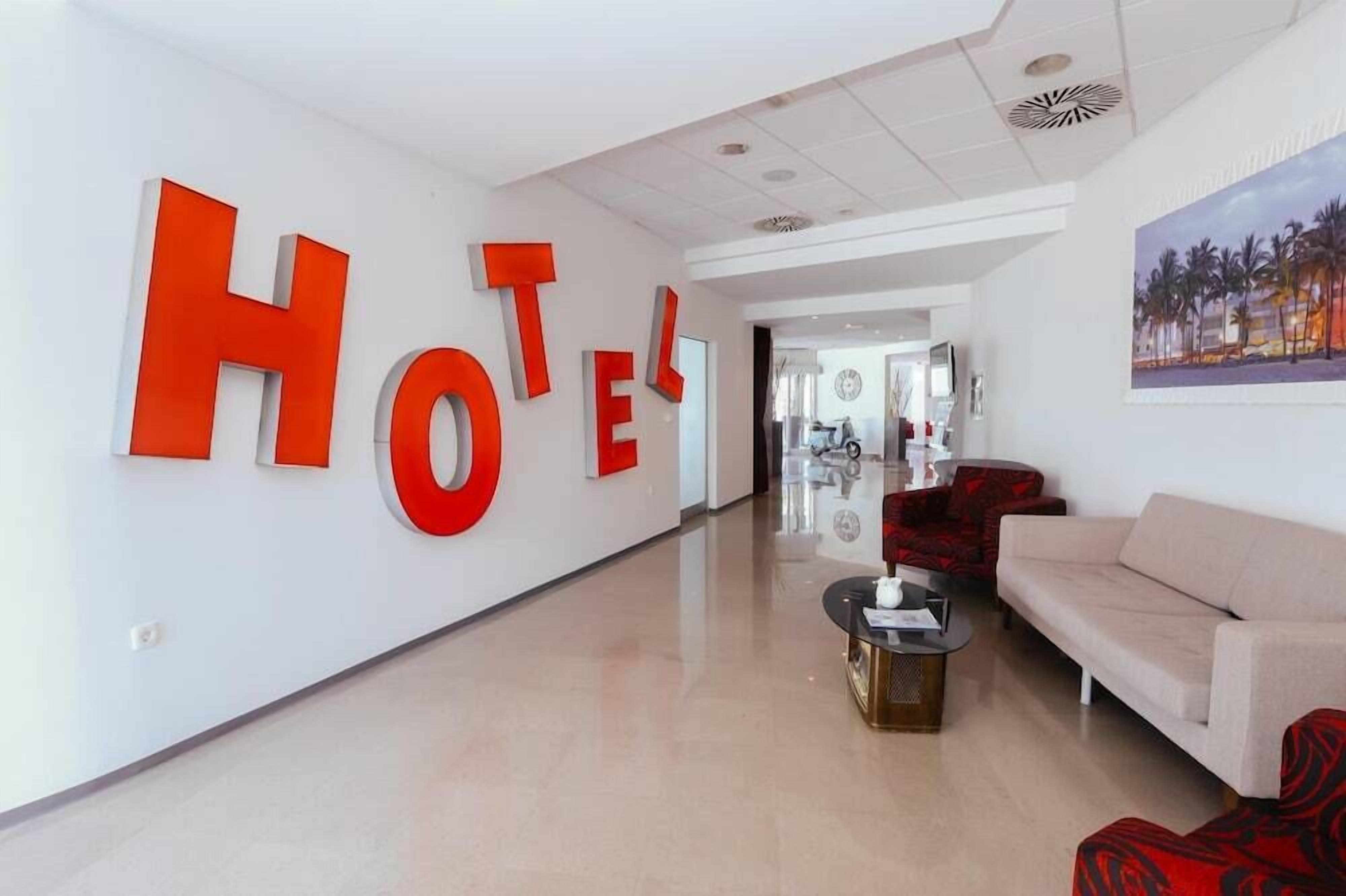 A hotel lobby with a large 'HOTEL' sign, a reception desk, a sofa, and a coffee table.