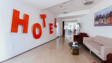 A hotel lobby with a large 'HOTEL' sign, a reception desk, a sofa, and a coffee table.