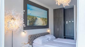 A bedroom with a bed, a painting of a beach, and a wardrobe.