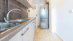 Eine moderne Küche mit Spüle aus Edelstahl, einem Kühlschrank mit zwei Türen und Holzschränken.