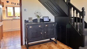 A kitchen with a window, a cabinet with drawers, and a staircase with a dark railing. - Ty'n Rardd Mountain Views Secure Garden Parking (Beaumaris)
