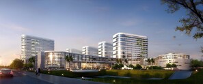 A modern multi-story building with a curved facade, large windows, and a central courtyard with a water feature. - Lavande Hotels Guangzhou North Railway Station (Guangzhou)