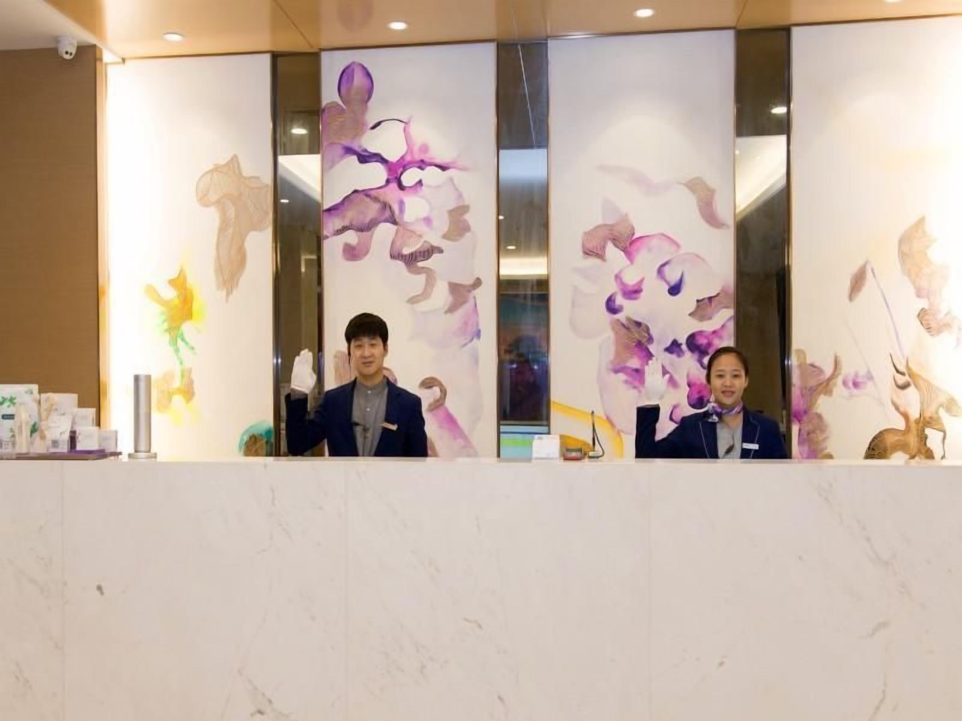 A reception desk with a marble top and a decorative wall with abstract floral patterns.