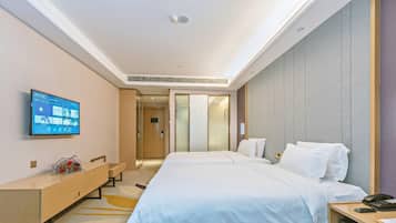 A hotel room with a large bed, a desk, a TV mounted on the wall, and a bathroom visible through a sliding door.