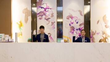 A reception desk with a marble top and a decorative wall with abstract floral patterns.
