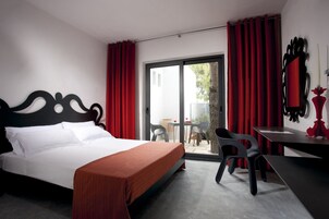 Habitación de hotel con cama, escritorio y silla. Hay un ventanal corredero que da a un espacio al aire libre.