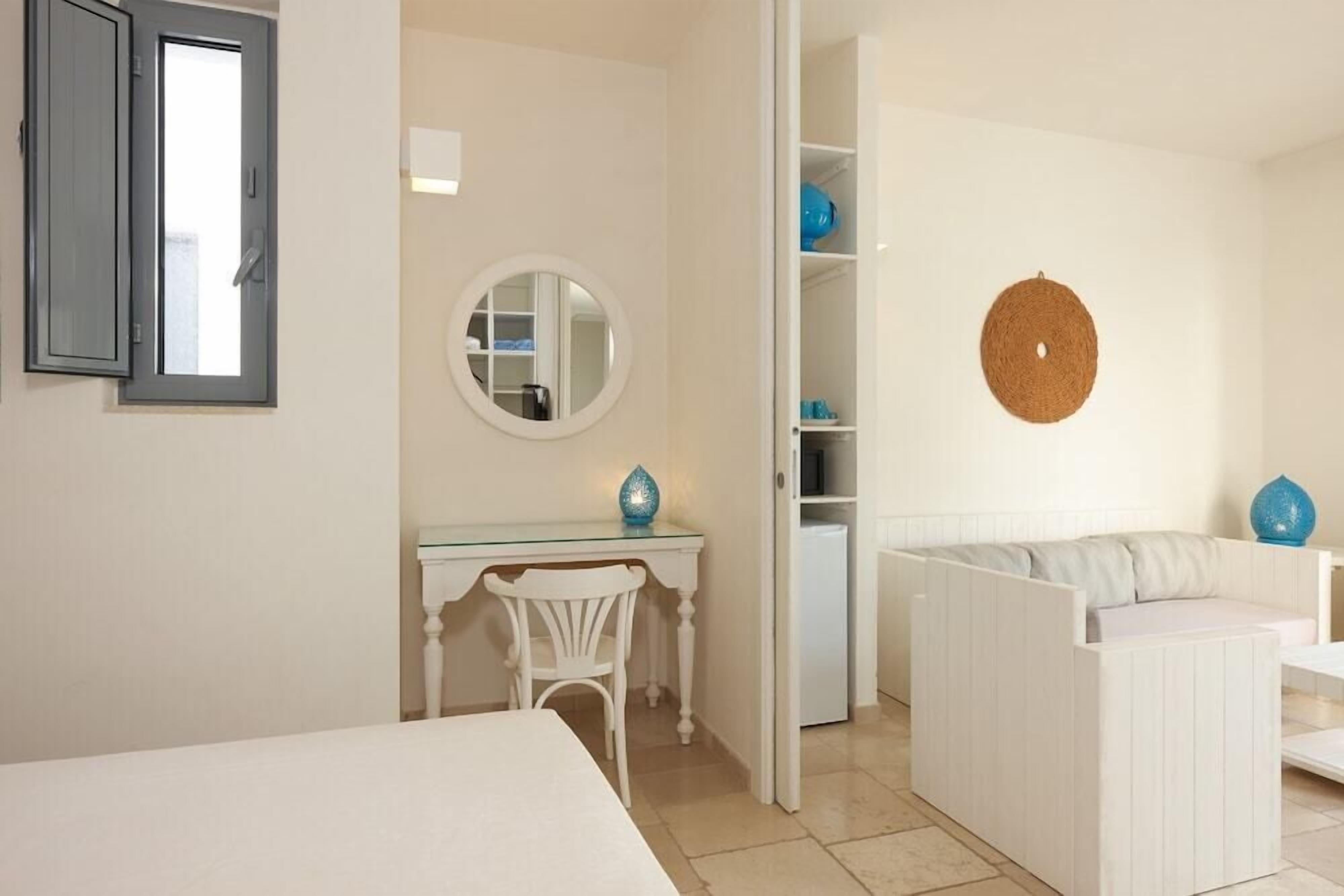 A room with a bed, a desk, a chair, a wardrobe, and a round mirror.