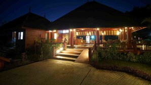 A wooden building with a covered outdoor seating area and a wooden deck leading to the entrance.