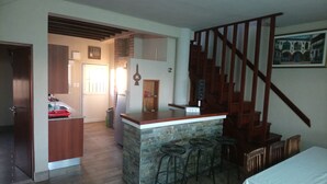 Eine Küche mit Barbereich, einer Treppe und einem Essbereich mit Tisch und Stühlen.
