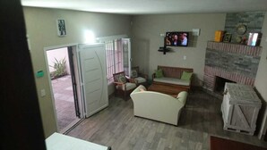 Ein Wohnzimmer mit einer Couch, einem an der Wand montierten Fernseher und einem Kamin.
