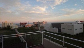 A residential area with modern buildings, a clear sky, and a distant view of the sea.
