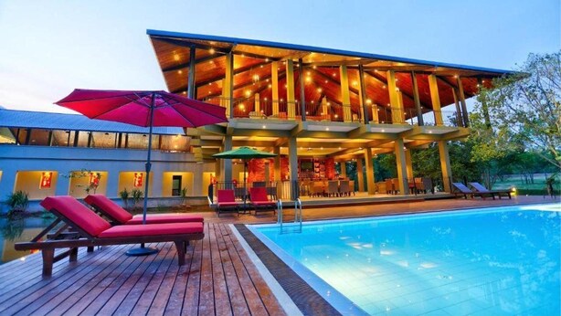 A modern hotel with a pool, outdoor seating, and a covered area with string lights. - Tropical Life Resort And Spa (Dambulla)