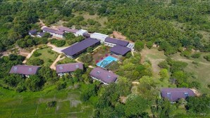 An aerial view of a residential area with multiple houses, a swimming pool, and surrounding greenery. - Tropical Life Resort And Spa (Dambulla)