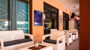A hotel lobby with wicker furniture, a poster, and a refrigerator. - Nikos Studios (Zakynthos)