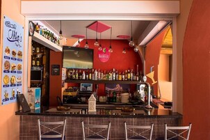 Una zona de bar con pared roja, luces colgantes y una variedad de botellas.
