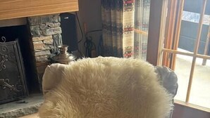 A chair with a fluffy white cover in a room with tiled flooring and a window.