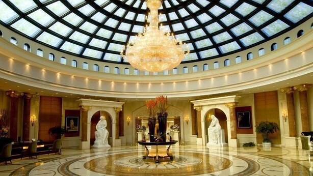 Un vestíbulo imponente con un techo abovedado alto, un candelabro central y estatuas clásicas.
