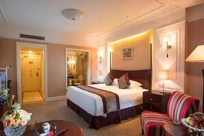 A hotel room with a large bed, bedside tables, a desk, a chair, and a dining table with flowers. - Zhejiang Tianducheng French Themed Resort (Hangzhou)