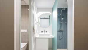 Ein modernes Badezimmer mit einem weißen Waschbecken, Spiegel und Dusche.