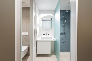 A modern bathroom with a white sink, mirror, and shower.